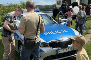 Zdjęcie przedstawia ojca z dzieckiem oglądający policyjny radiowóz
